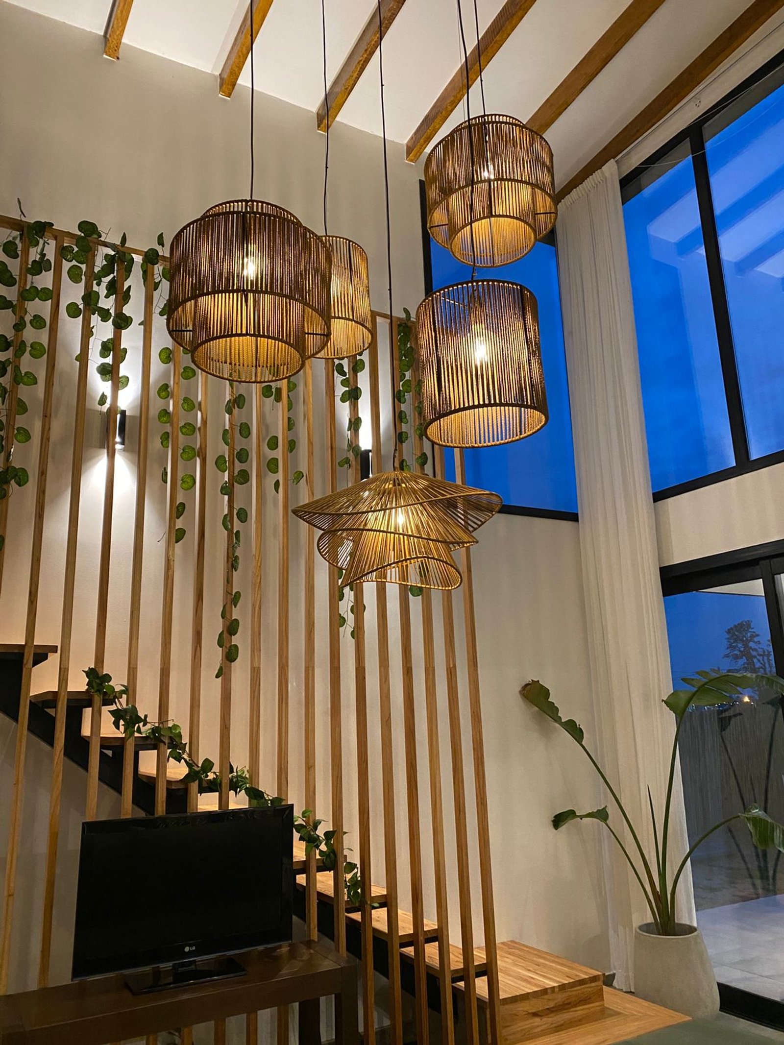 Interior com escadas flutuantes e luminárias de ratã — projeto Casa Tulum, por vetainteriores, em Pergamino